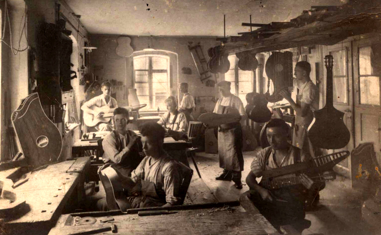 Die Werkstatt von Josef Hoyer in den 1920er Jahren. Um den zentral im Raum stehenden Josef Hoyer gruppieren sich seine Frau, drei Söhne und drei weitere Mitarbeiter